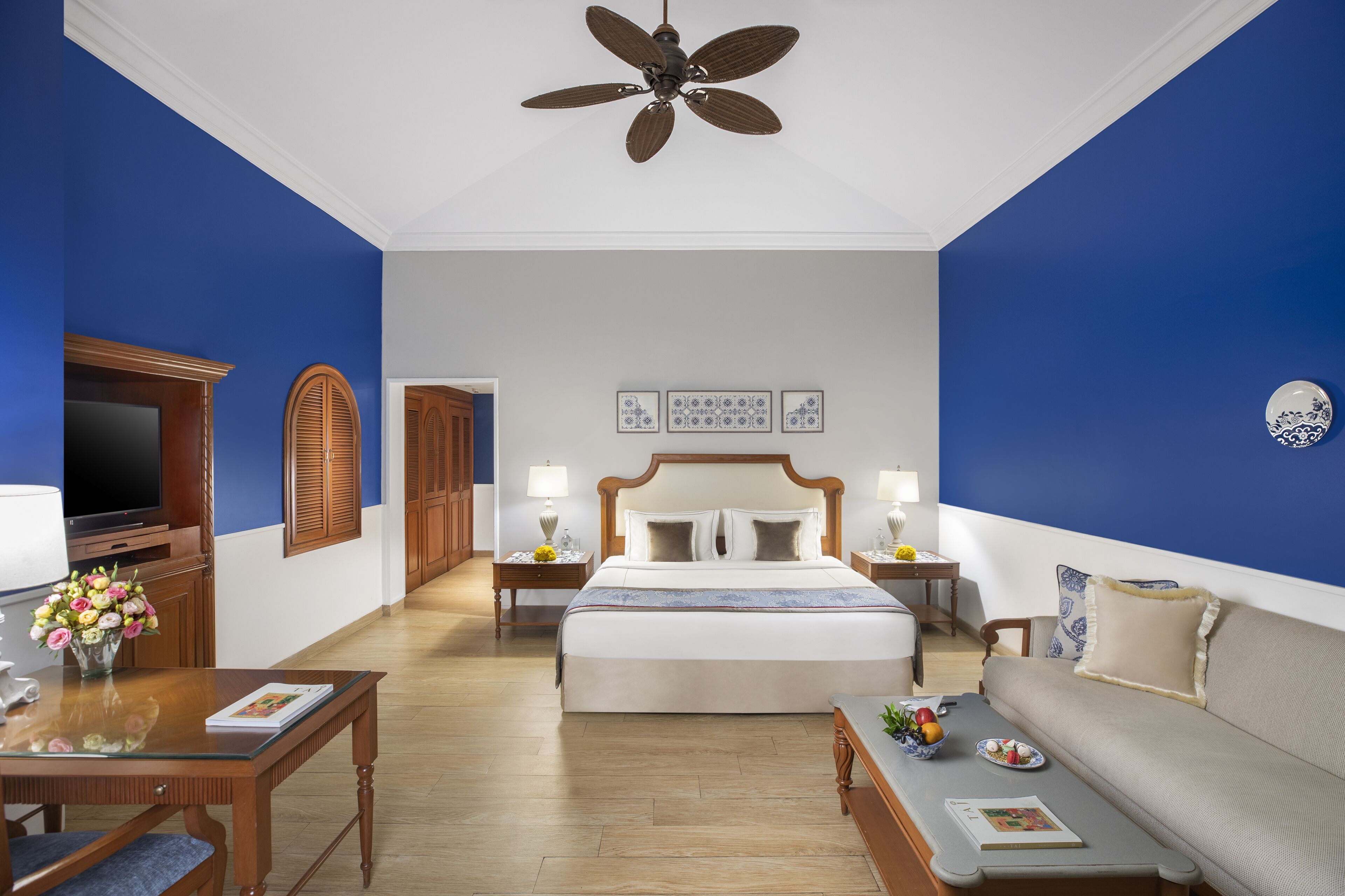 A hotel room with a bed, a sofa, a TV, and a ceiling fan.
