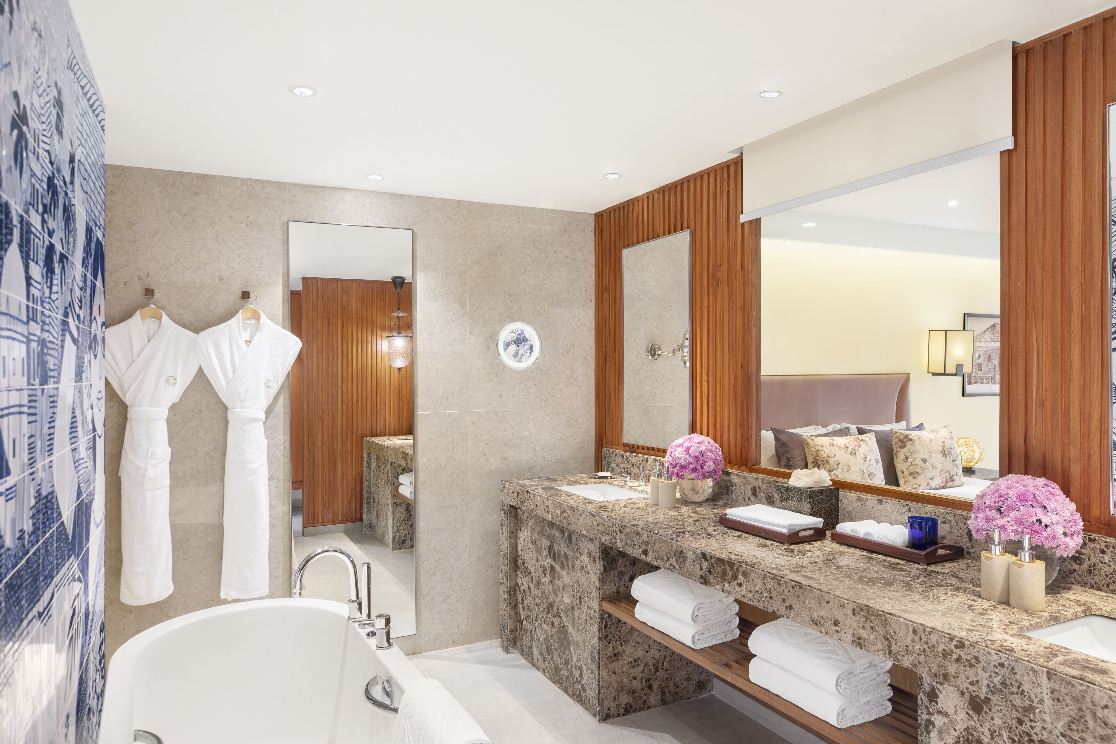 A modern bathroom with a large mirror, two sinks, a bathtub, and wooden paneling.