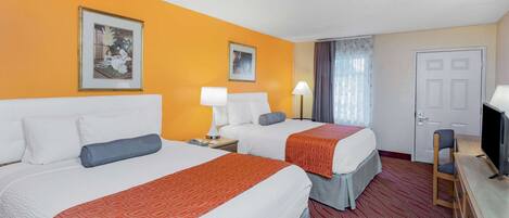 Habitación de hotel con dos camas, televisión y escritorio.