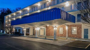 Un hotel de varios pisos con un corredor cubierto y un área de estacionamiento.