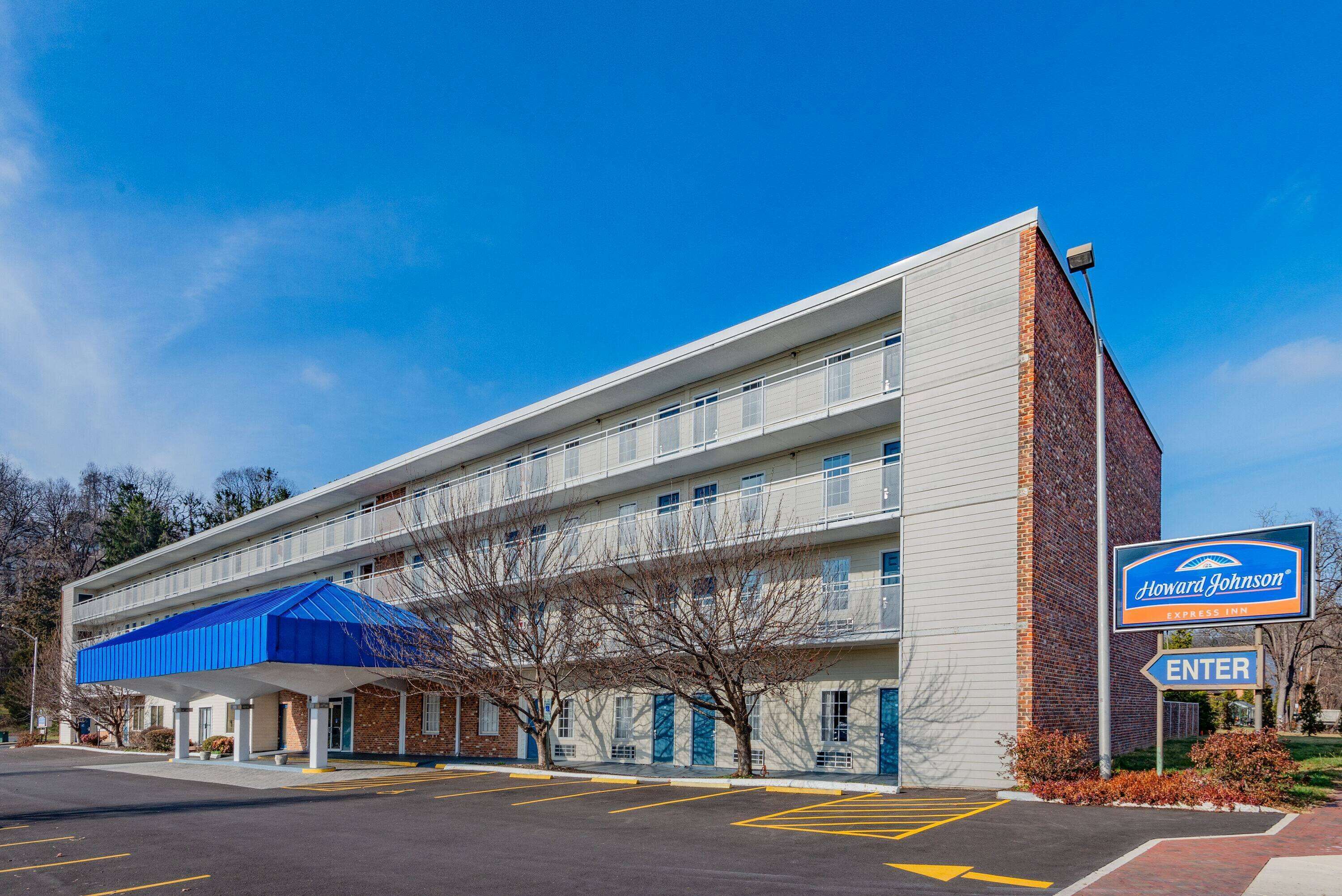 A Howard Johnson Express Inn with a blue awning, a parking lot, and a clear blue sky.