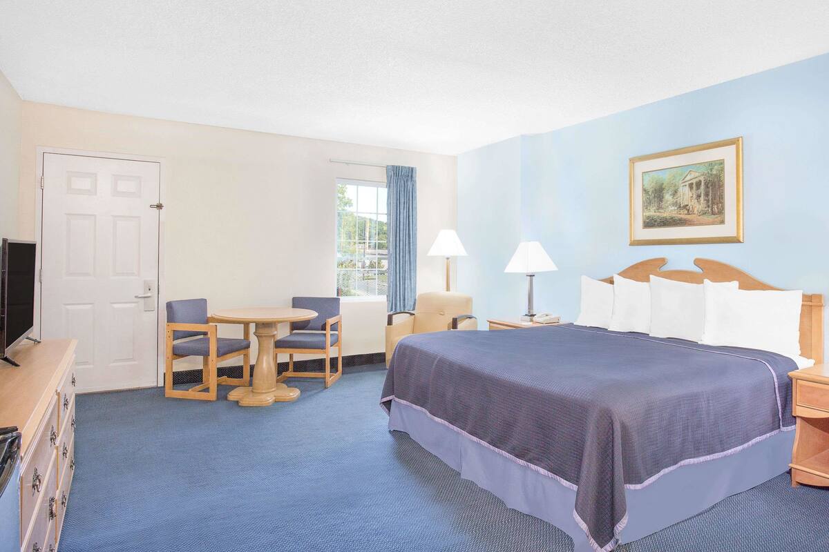 Une chambre d’hôtel équipée d’un lit, d’un bureau, d’une chaise, d’une télévision et d’une fenêtre avec des rideaux.