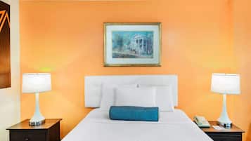 Una camera d'albergo con un letto, due comodini, una lampada su ciascun comodino, un quadro appeso al muro e un tappeto decorato sul pavimento.