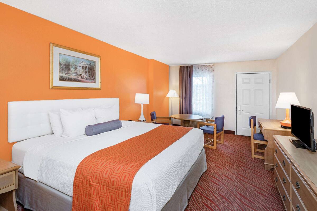 Une chambre d’hôtel avec un grand lit, un bureau, une chaise, une télévision et une porte.
