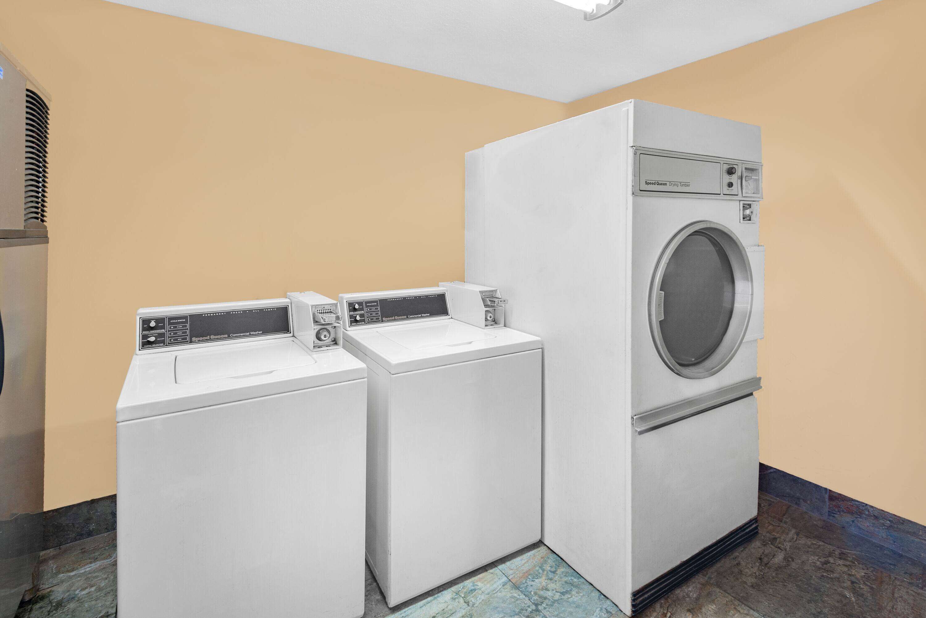 A laundry room with two washing machines and a dryer.
