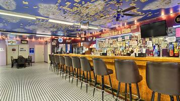 A bar with a ceiling decorated with dollar bills, a bar counter with stools, and a sign reading "Knight's Bar & Club".