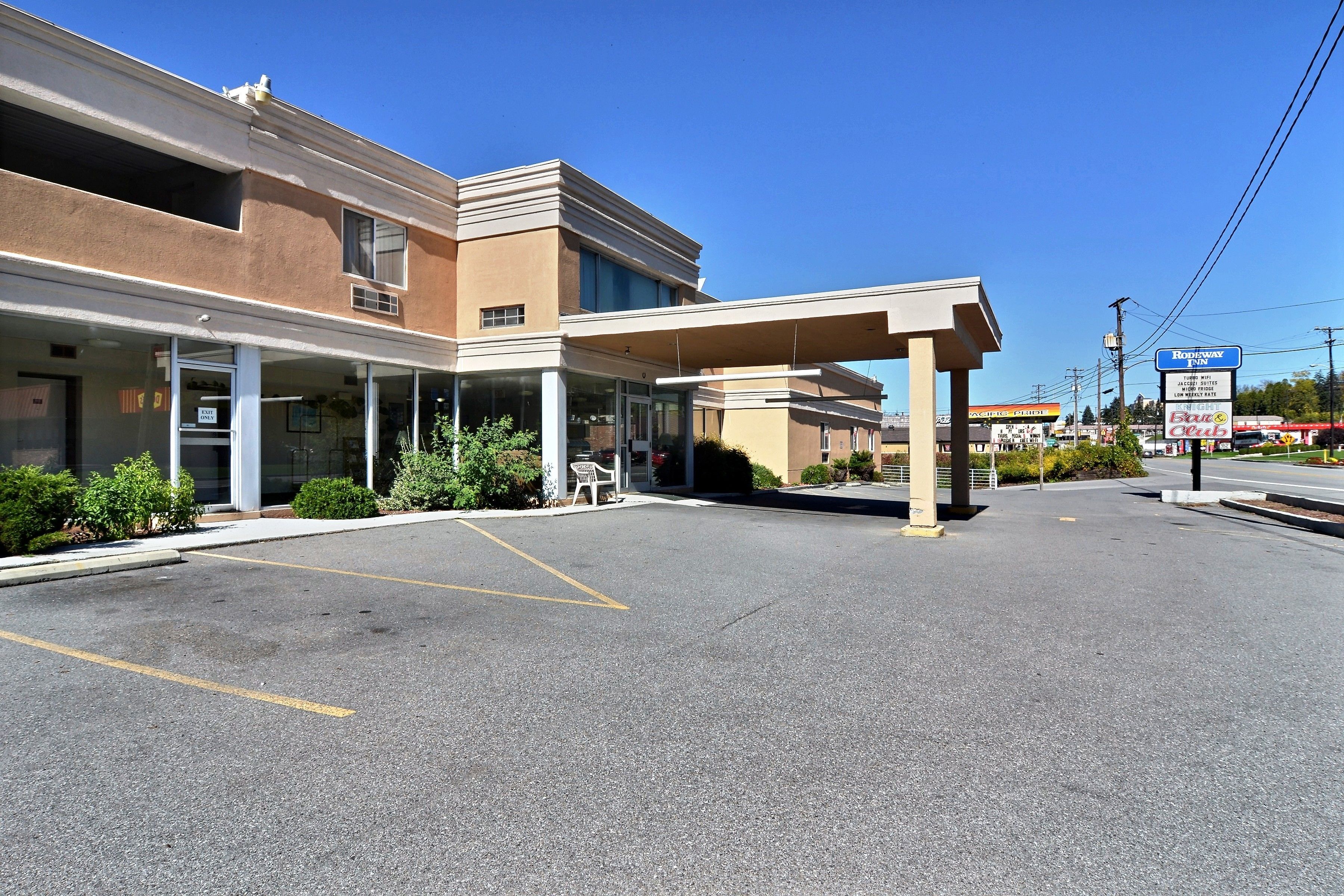 A commercial building with a covered entrance, a parking lot, and a sign for 'Rodeway'.