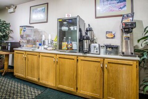 A kitchenette with a coffee machine, toaster, and various food items on the counter.