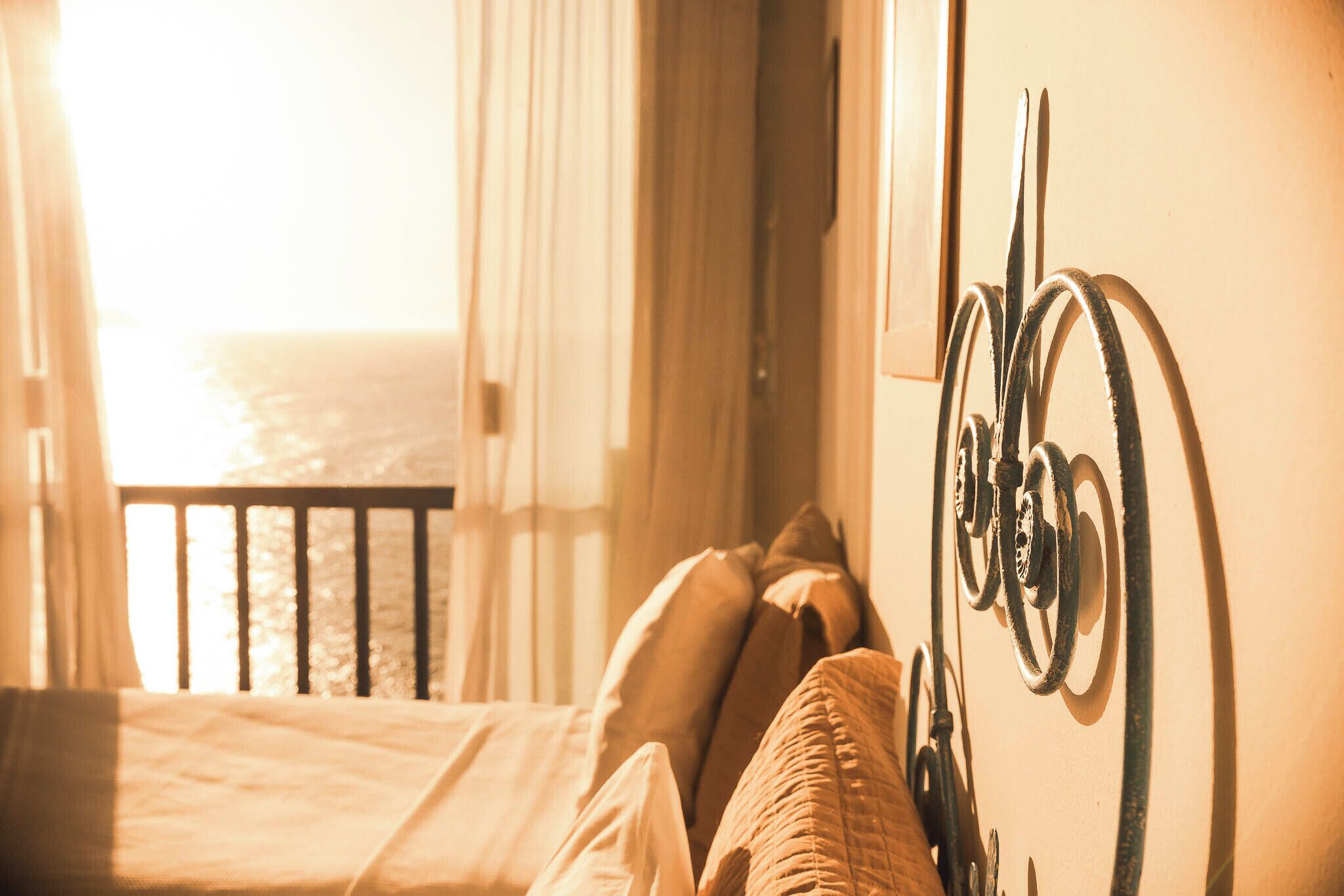 Una habitación con una cama, almohadas y un adorno metálico en la pared.
