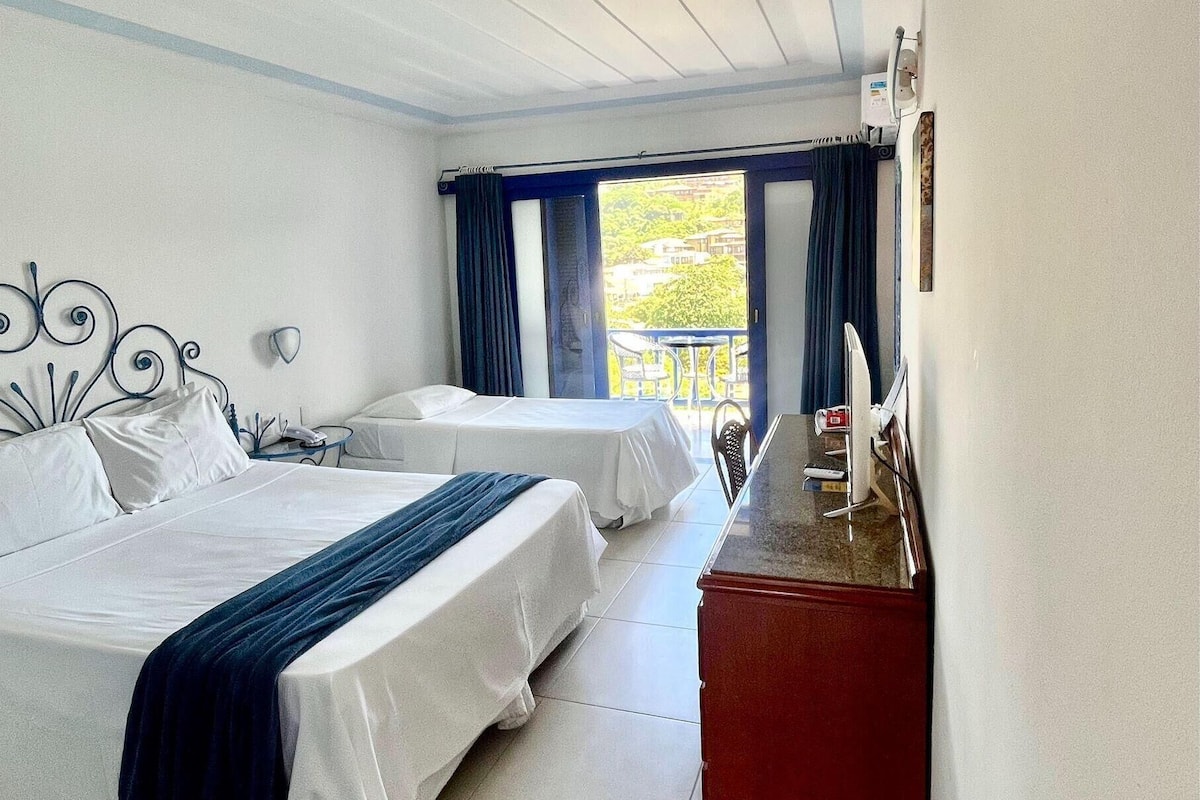 A hotel room with two beds, a small desk, and a view of the outdoors.