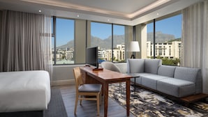 A hotel room with a bed, a desk, a sofa, and a TV. - Protea Hotel by Marriott Cape Town Waterfront Breakwater Lodge (Cape Town)