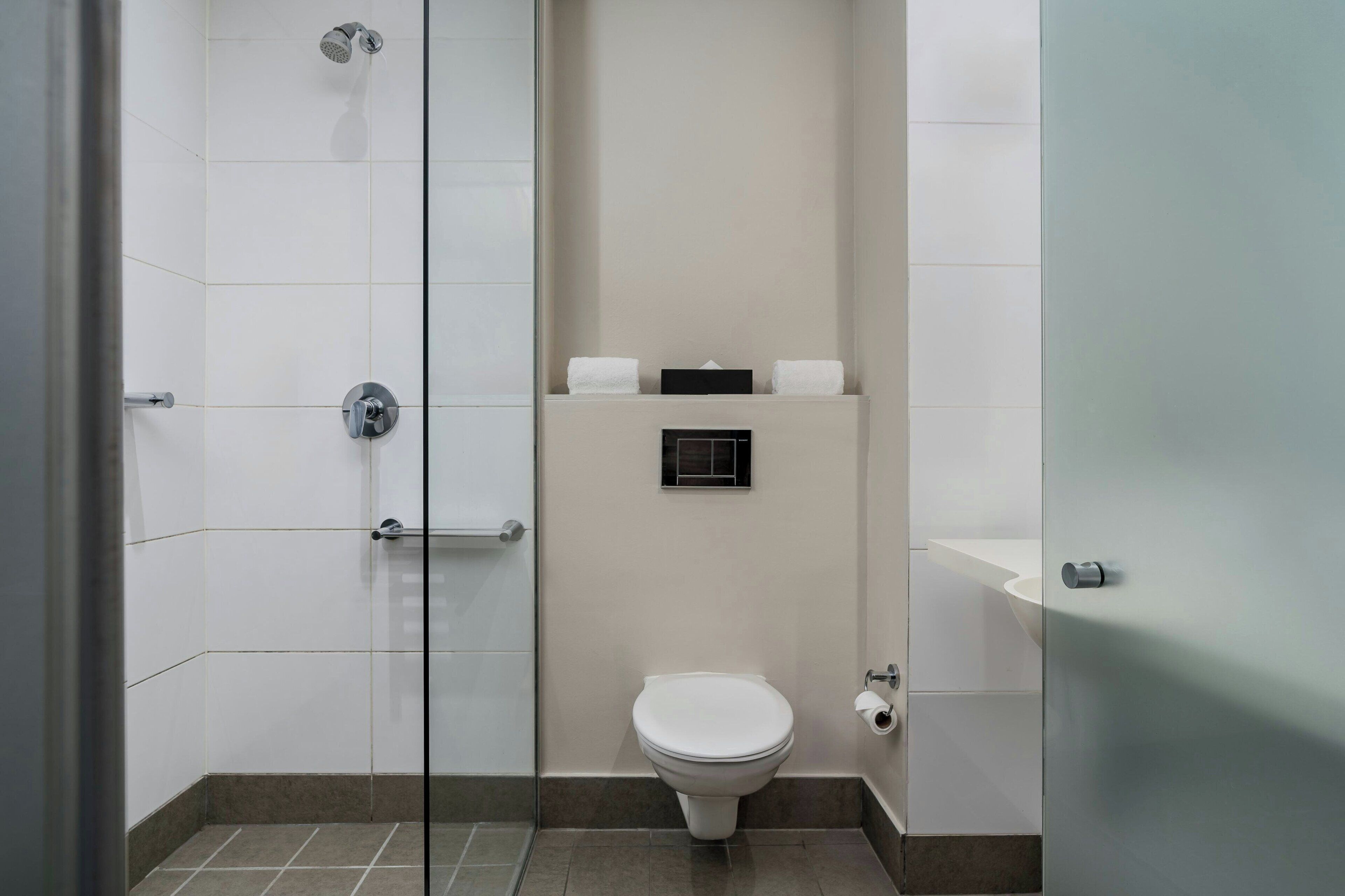 A modern bathroom with a glass shower enclosure, a toilet, and a sink.