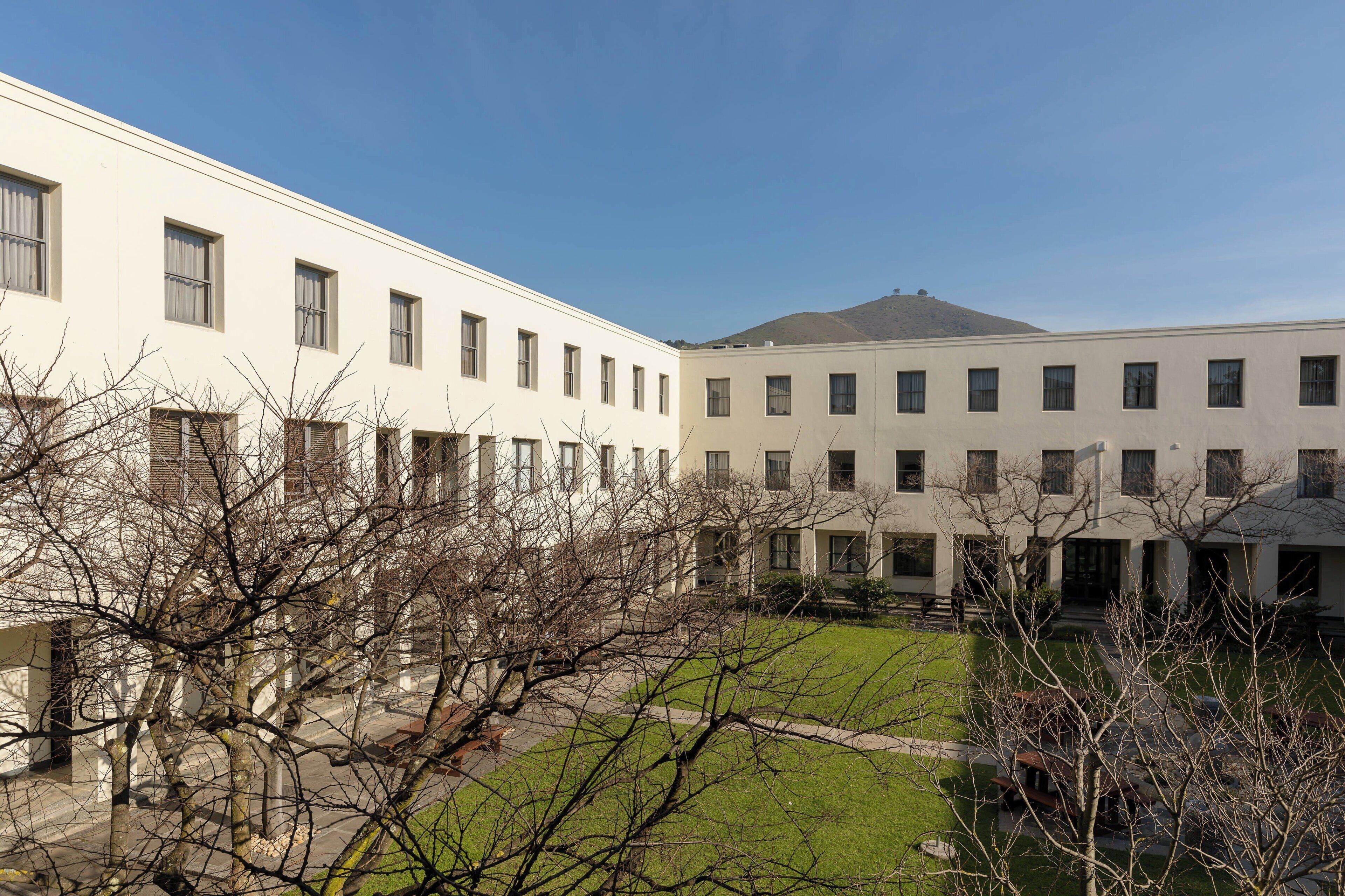 A courtyard with a building featuring a series of windows and a flat roof.