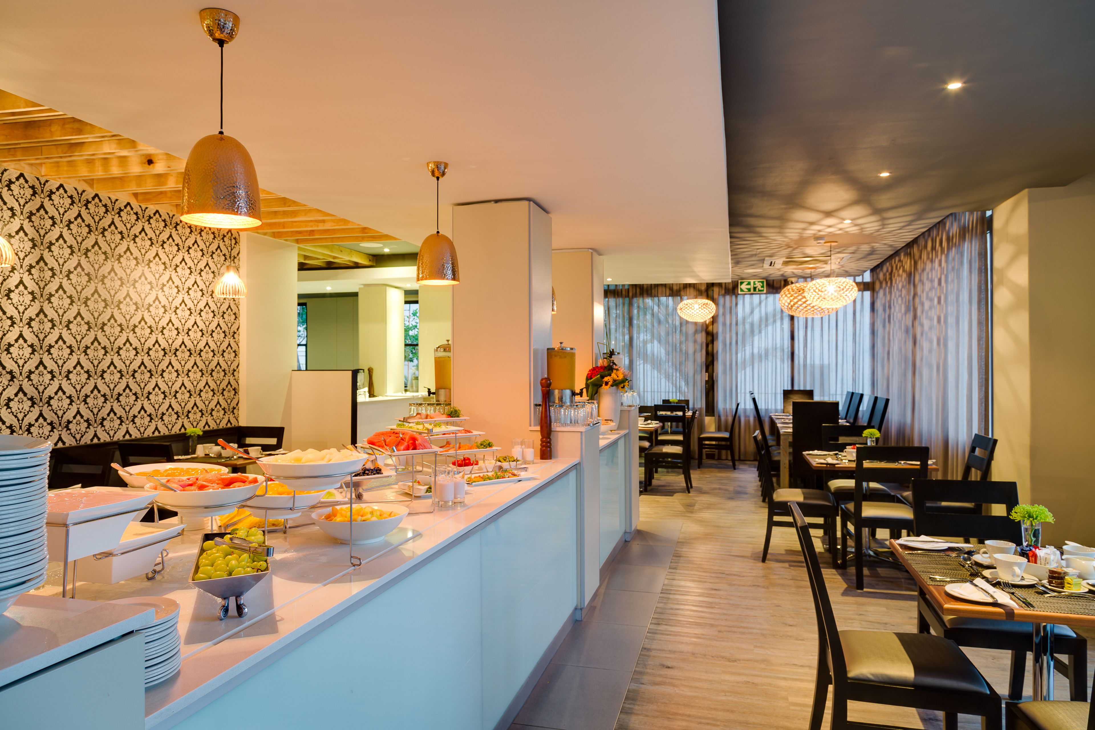 A buffet area with various food items and a dining area with tables and chairs.