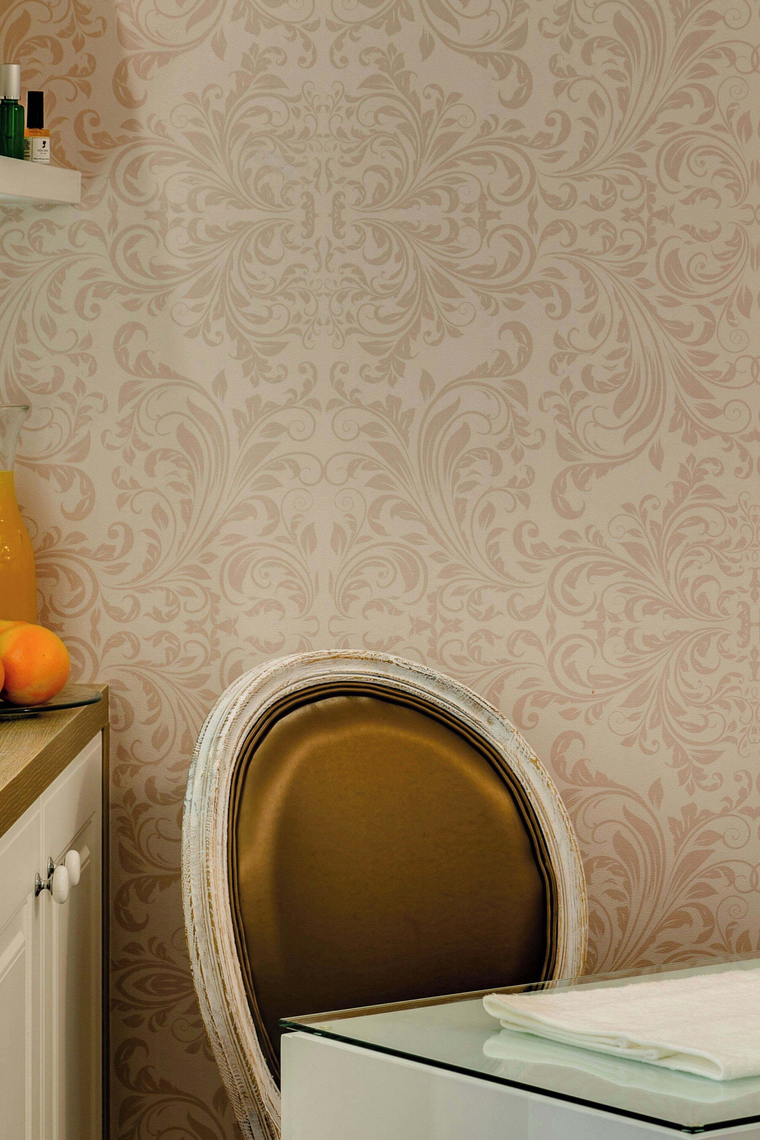 A bathroom with a patterned wallpaper, a mirror with a gold frame, and a glass-topped table with a folded towel.