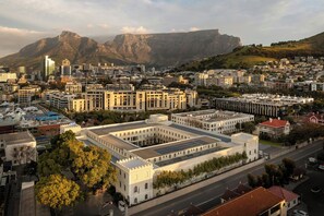 A cityscape with a prominent white building with a central courtyard and solar panels, surrounded by other buildings and a mountain in the background. - Protea Hotel by Marriott Cape Town Waterfront Breakwater Lodge (Cape Town)