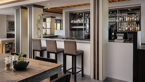 A modern bar area with a bar counter, stools, and a variety of bottles and glasses. - Protea Hotel by Marriott Cape Town Waterfront Breakwater Lodge (Cape Town)