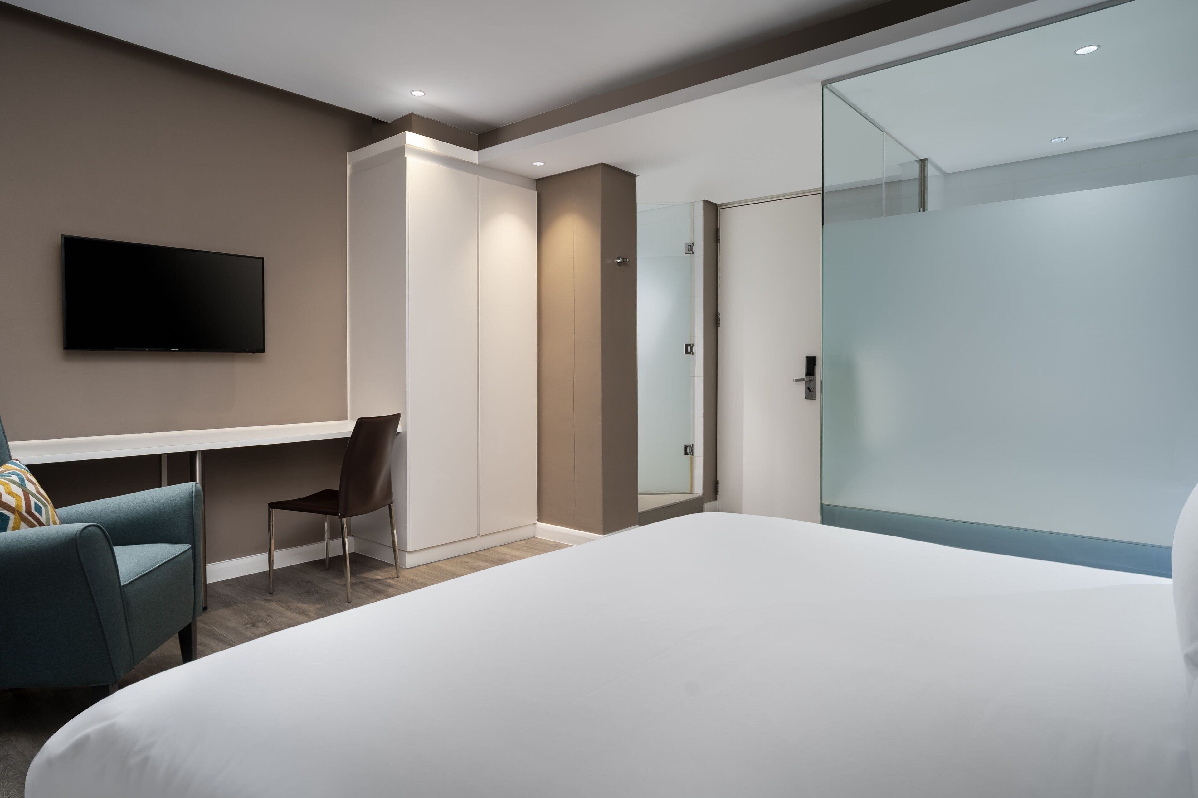 Una habitación de hotel moderna con una cama grande, un escritorio, una silla y un televisor.