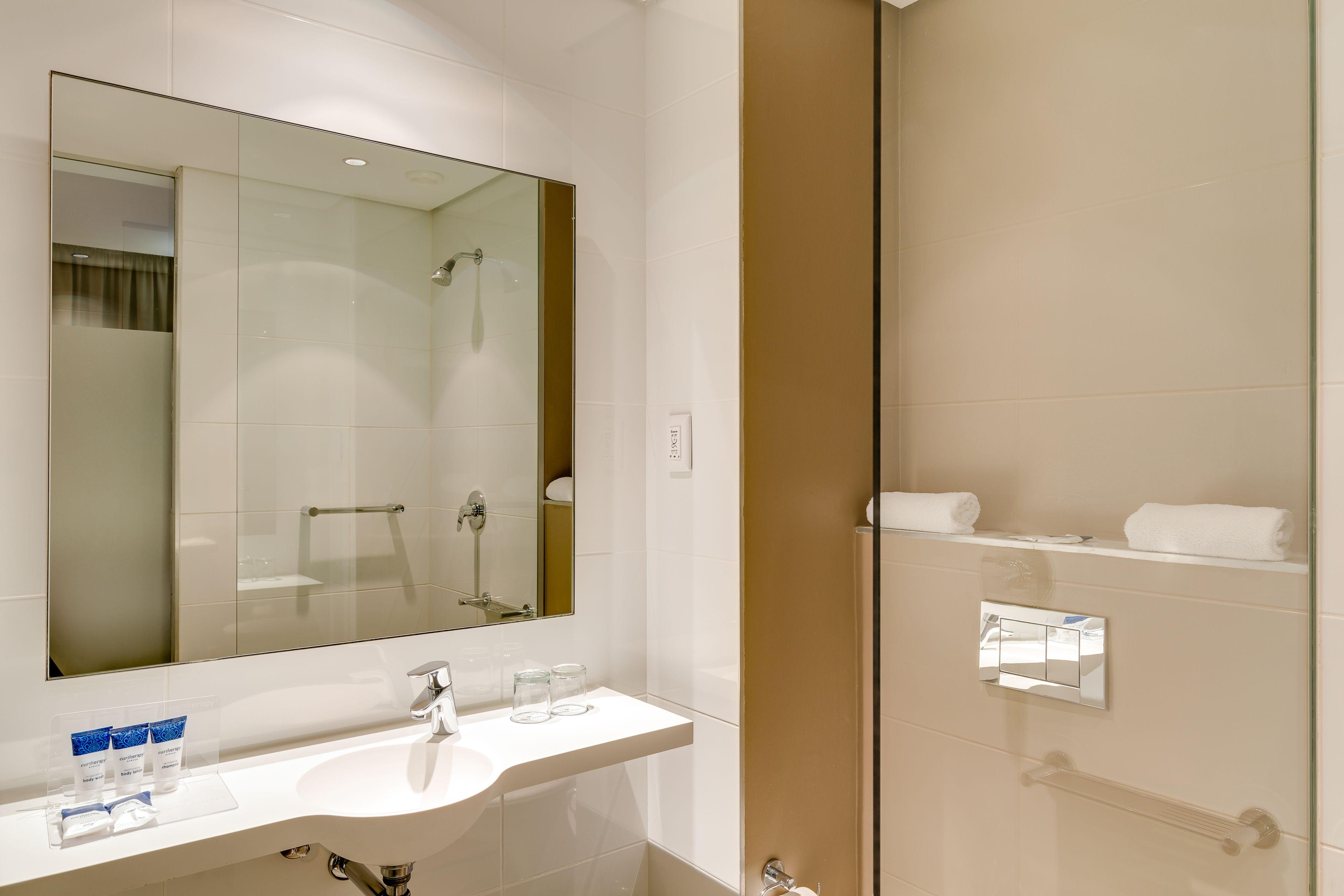 Een moderne badkamer met een grote spiegel, een wastafel en een douche met glazen wanden.