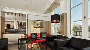 A modern living room with a black leather sofa, a glass coffee table, and a painting on the wall. - Hotel De La Jatte (Neuilly-sur-Seine)