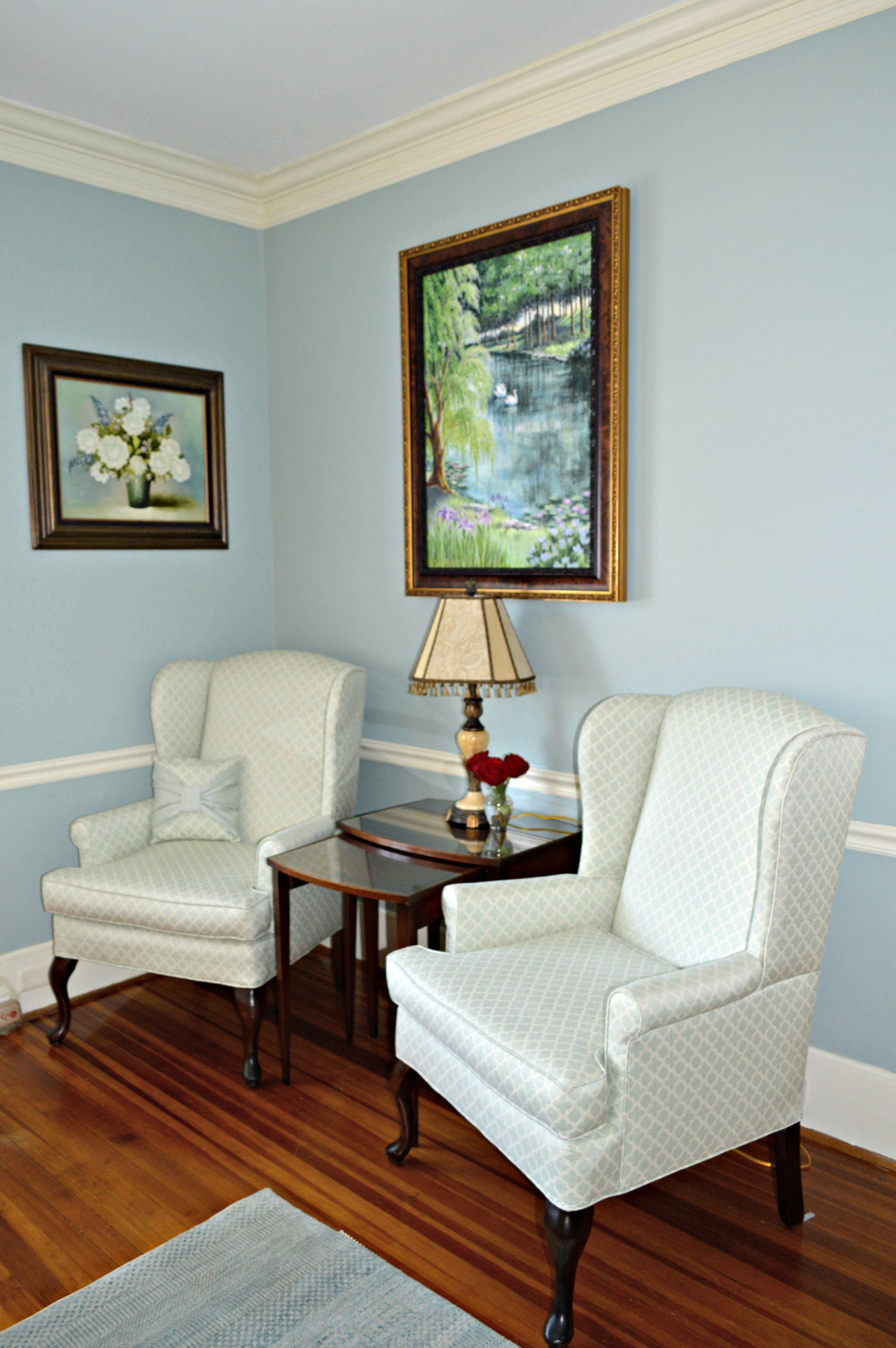 A room with two armchairs, a wooden coffee table, and a painting on the wall.