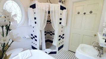Un baño con un lavamanos blanco, un inodoro blanco, una bañera blanca, una ducha blanca con diseño de cuadros y una puerta blanca con ventana.