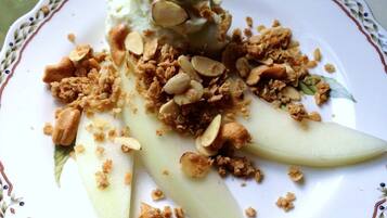 A plate with sliced pears, granola, and almonds.