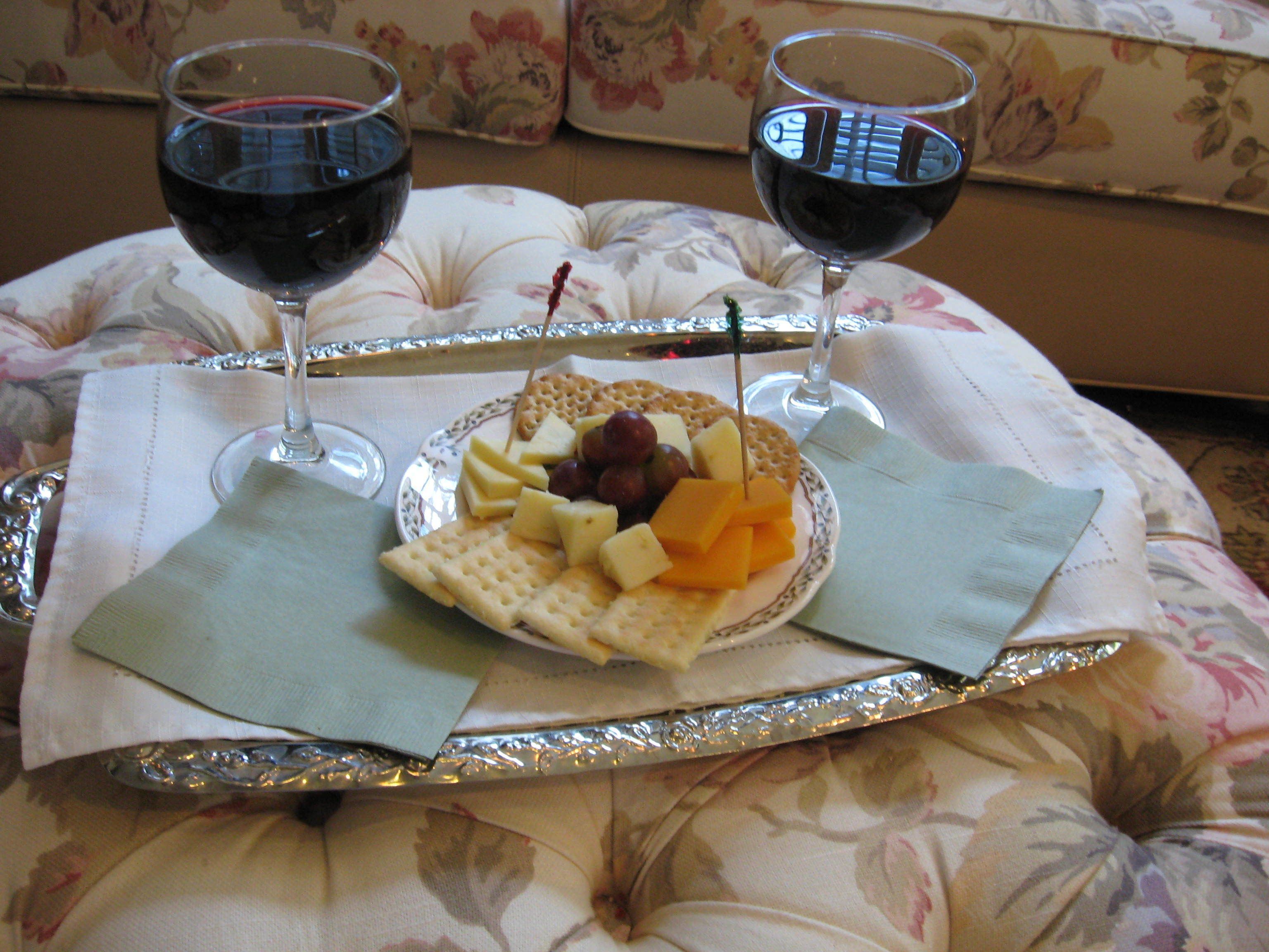 Un plateau avec du fromage, des crackers et des raisins, posé sur un canapé à motifs floraux.