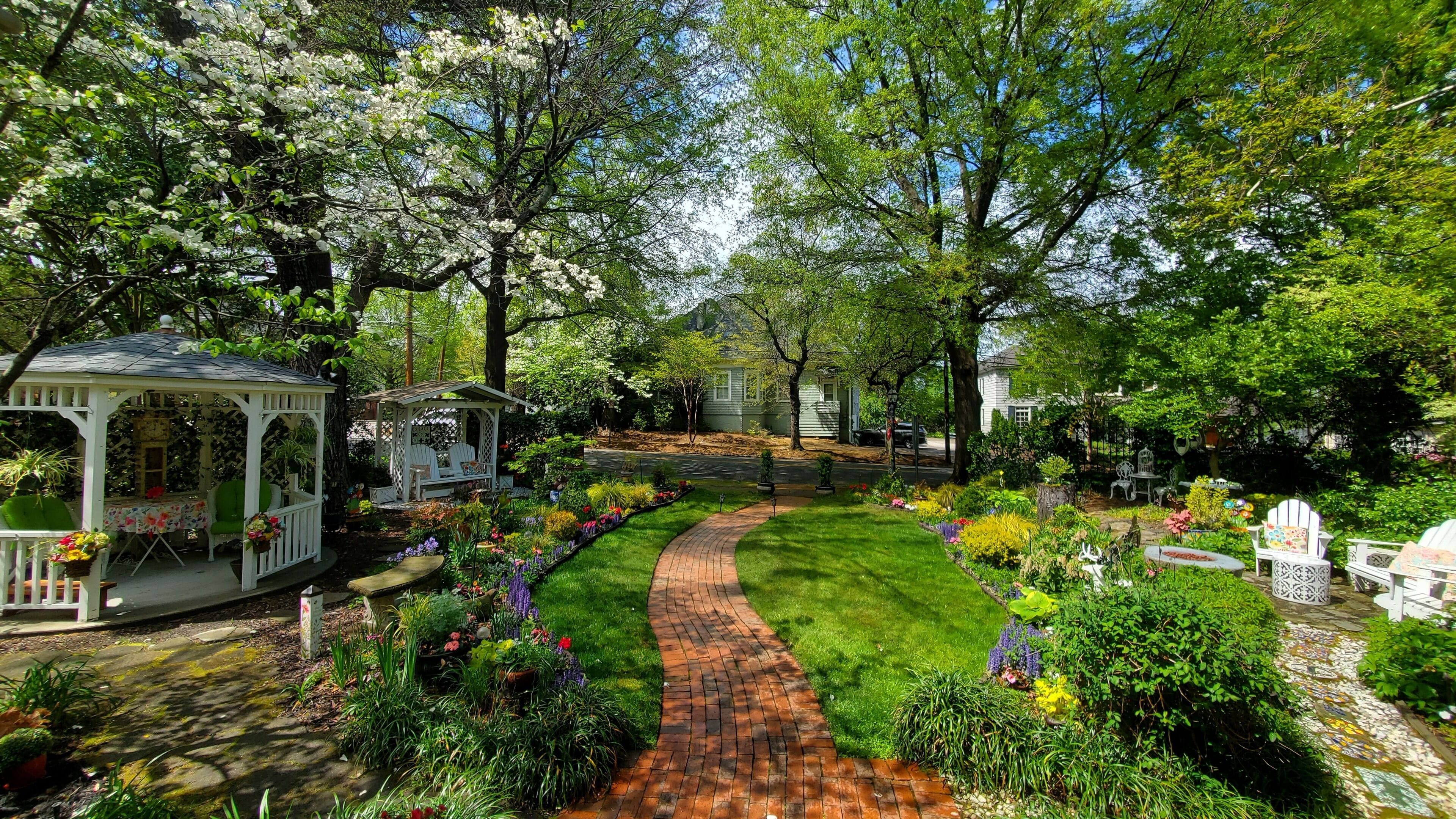 A garden with a paved walkway, a gazebo, and various plants.