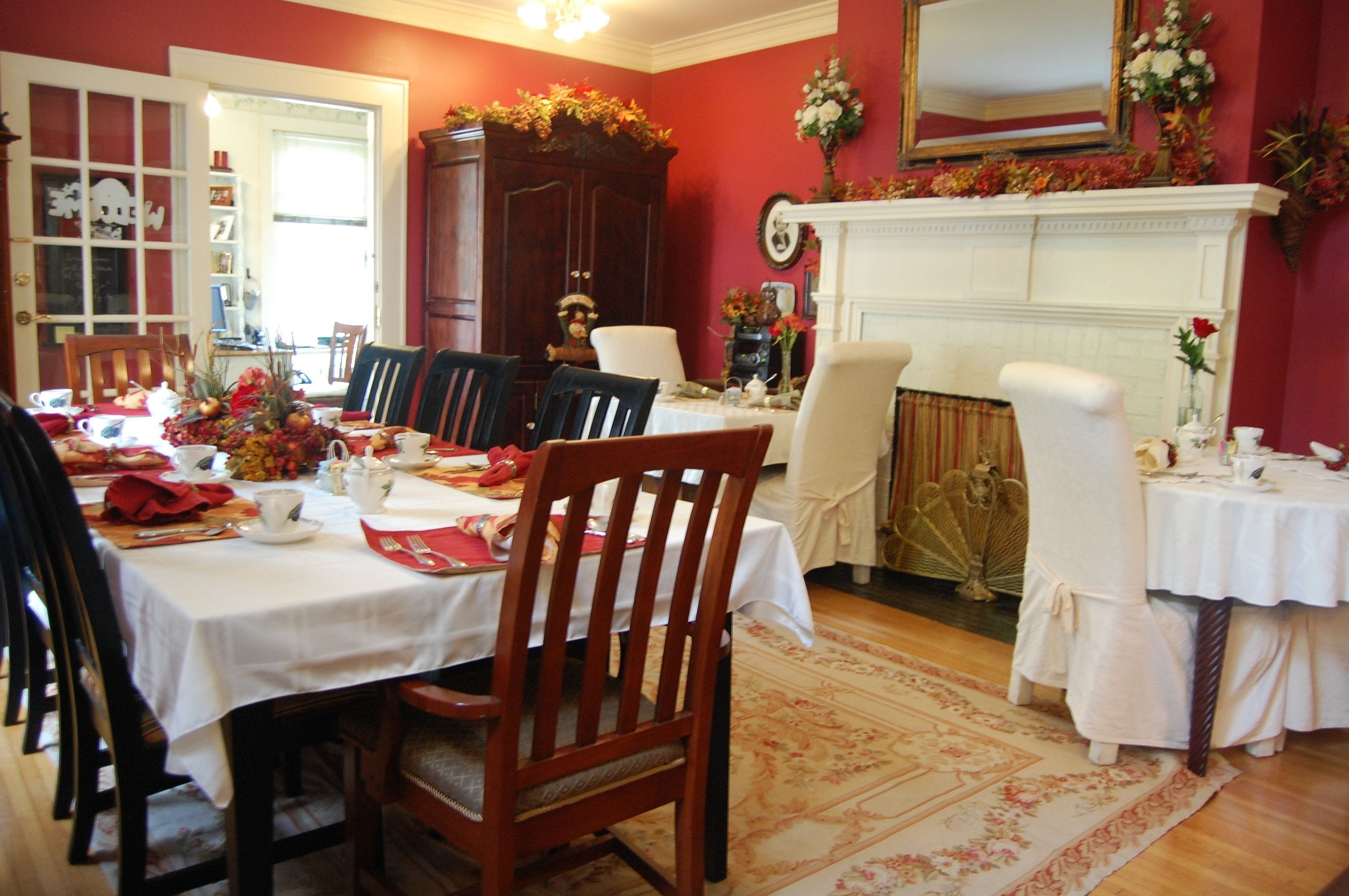 A dining room with a white table set for a meal, surrounded by wooden chairs.