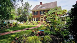 A two-story brick house with a well-maintained garden, a driveway, and a street sign for Pettigru Street. - Pettigru Place Bed & Breakfast (Greenville)