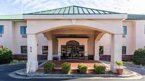 A hotel entrance with a covered walkway, a bench, and a small garden area. - Econo Lodge Inn & Suites Marietta near Dobbins ARB (Marietta)