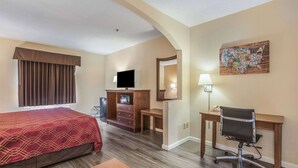 A hotel room with a bed, a desk, a chair, a television, a dresser, and a map artwork on the wall. - Econo Lodge Inn & Suites Marietta near Dobbins ARB (Marietta)