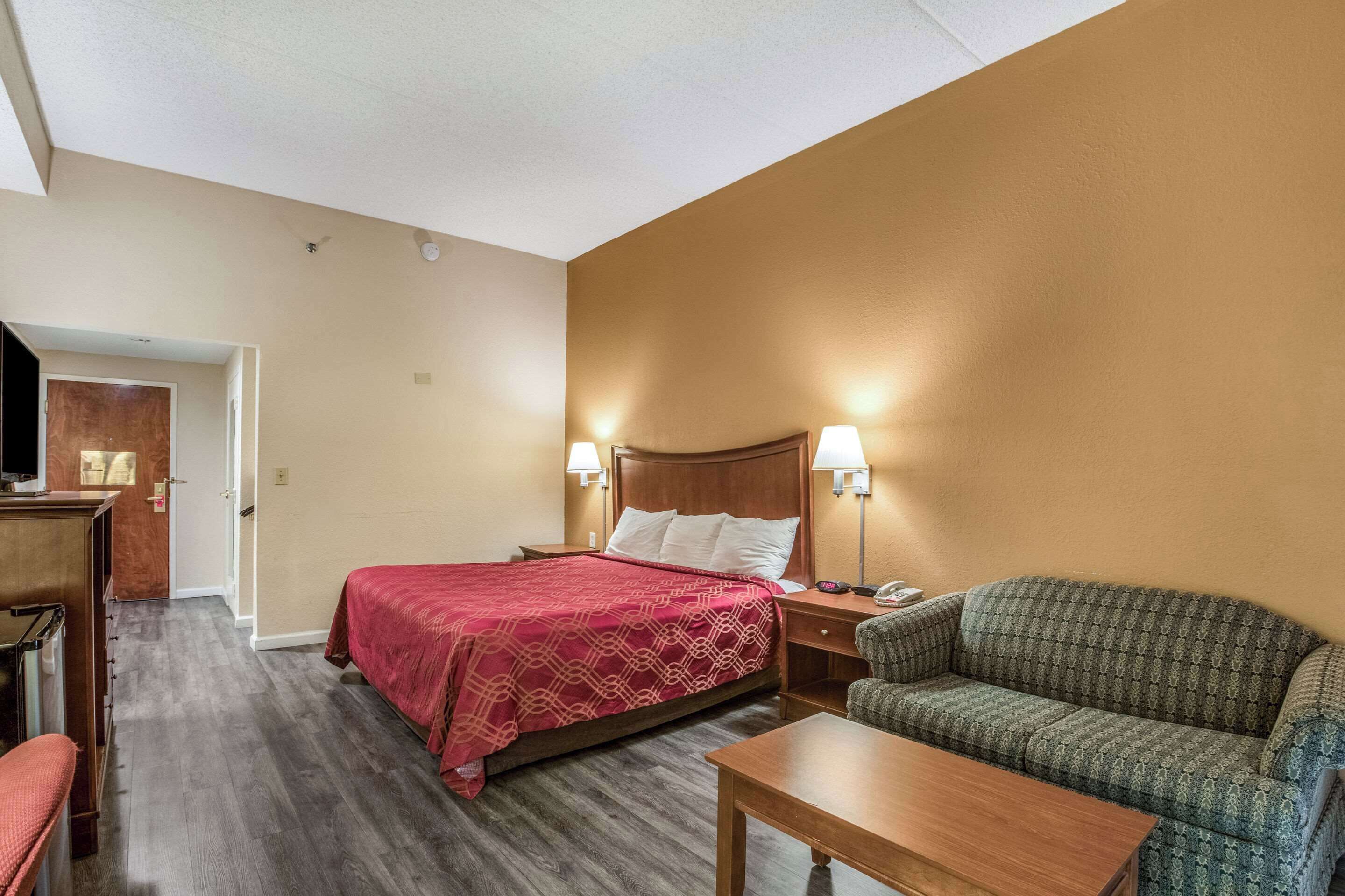A hotel room with a bed, a sofa, a desk, and a television.