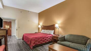 A hotel room with a bed, a sofa, a desk, and a television.