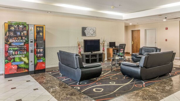 A lobby with a vending machine offering snacks and drinks, a flat-screen TV, and two leather sofas. - Econo Lodge Inn & Suites Marietta near Dobbins ARB (Marietta)