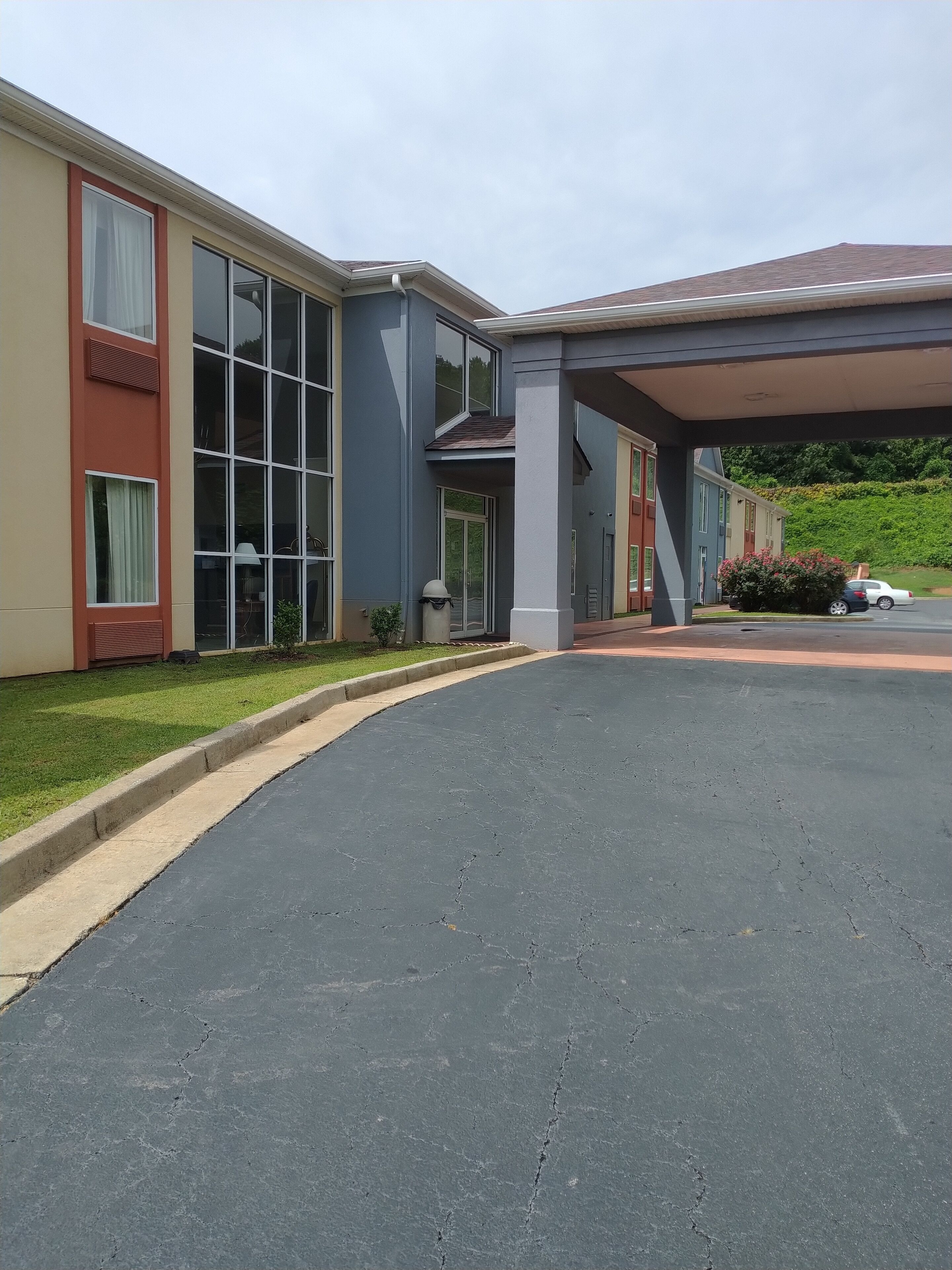 A modern building with large windows, a covered entrance, and a parking area.