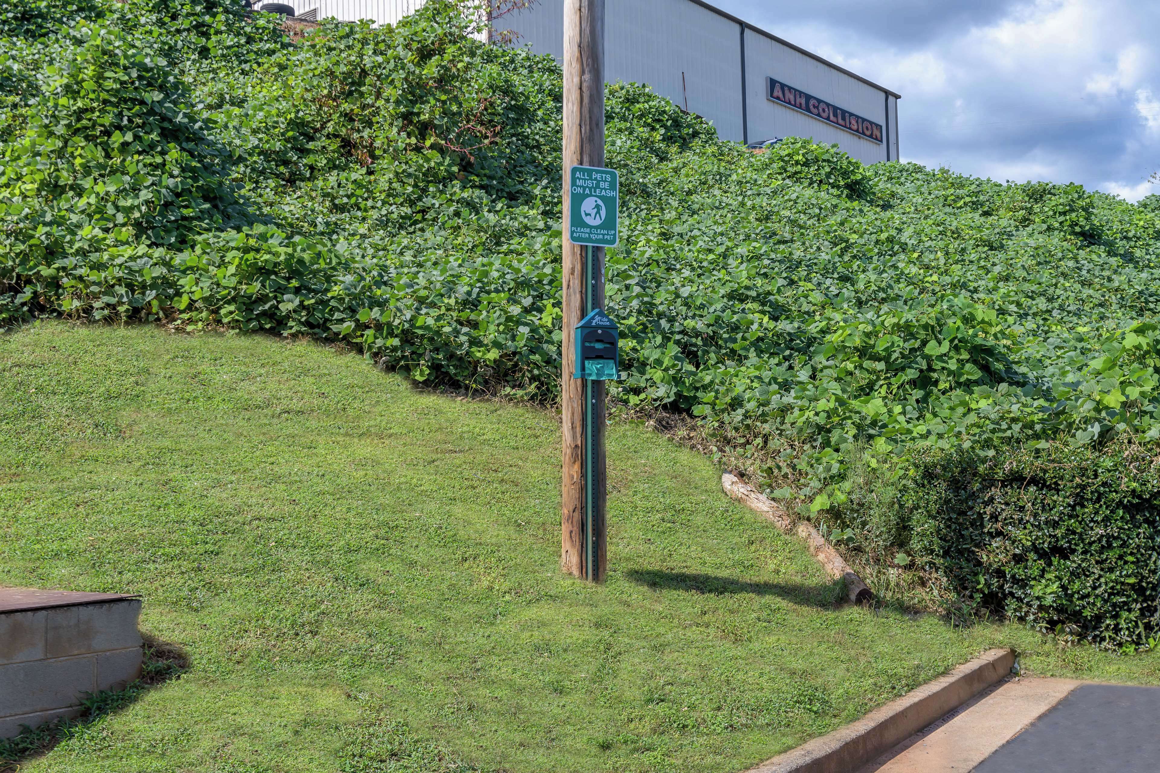 A grassy area with a signpost and a building in the background.