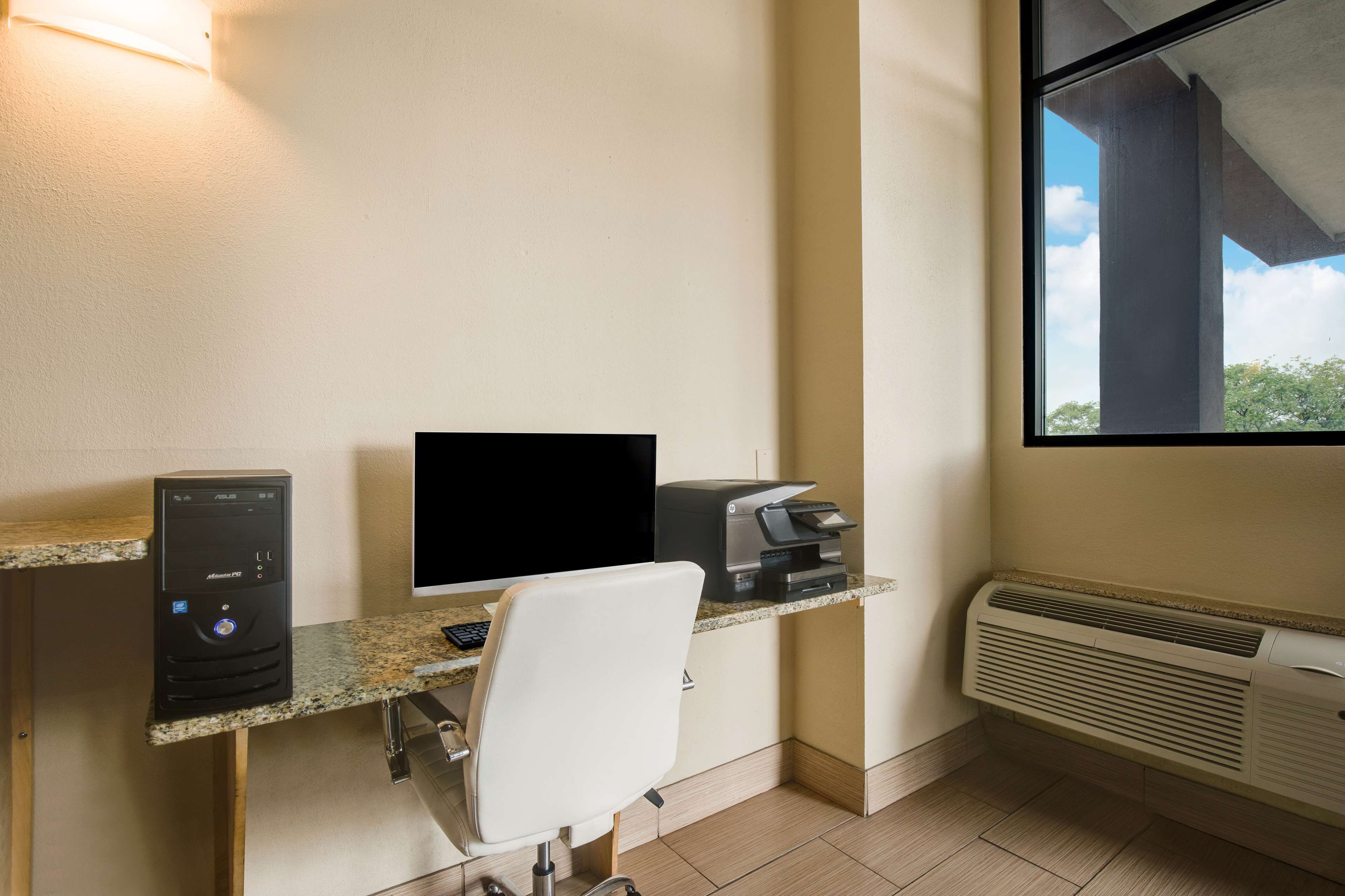 A home office with a desktop computer, printer, and chair.
