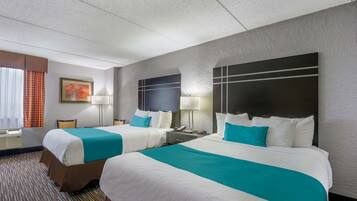 Habitación de hotel con dos camas, un ventanal con cortinas, un cuadro en la pared y un cabecero con televisor.