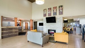 A hotel lobby with a reception desk, seating area, flat-screen TV, and a fireplace.