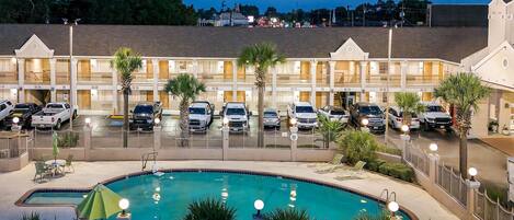 Un hotel con piscina, varios espacios de estacionamiento y un área exterior cercada.