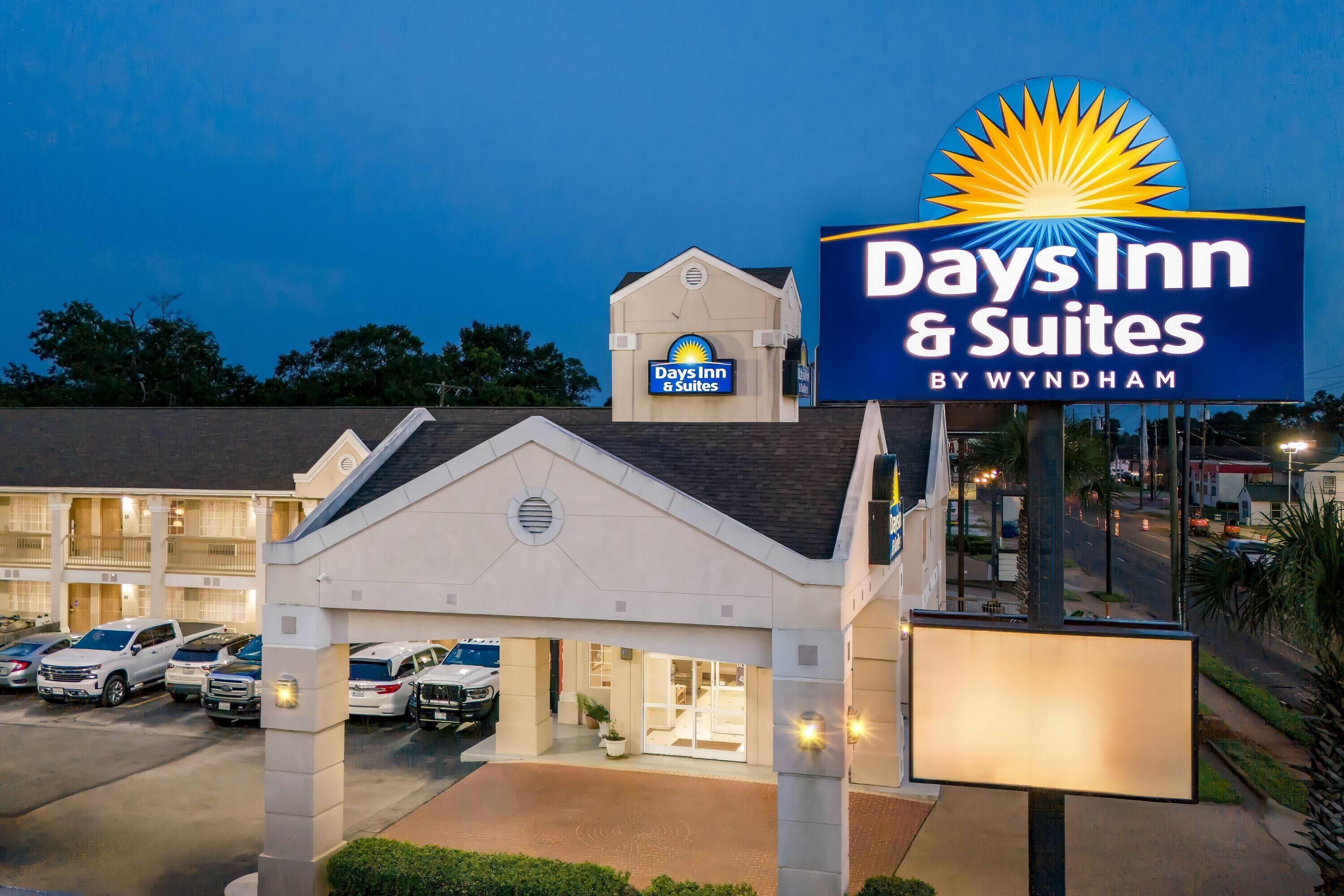 A Days Inn & Suites by Wyndham with a parking lot and a building entrance.