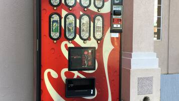 A vending machine with various drink options, a payment interface, and a Coca-Cola logo.