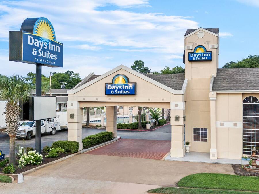 Un Days Inn & Suites by Wyndham con entrada despejada, zona de estacionamiento y césped bien cuidado.