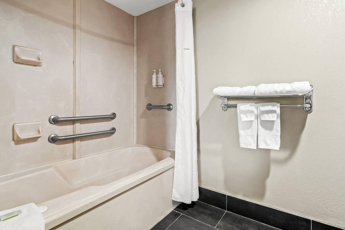 A modern bathroom with a bathtub, a shower area, and a towel rack with towels.