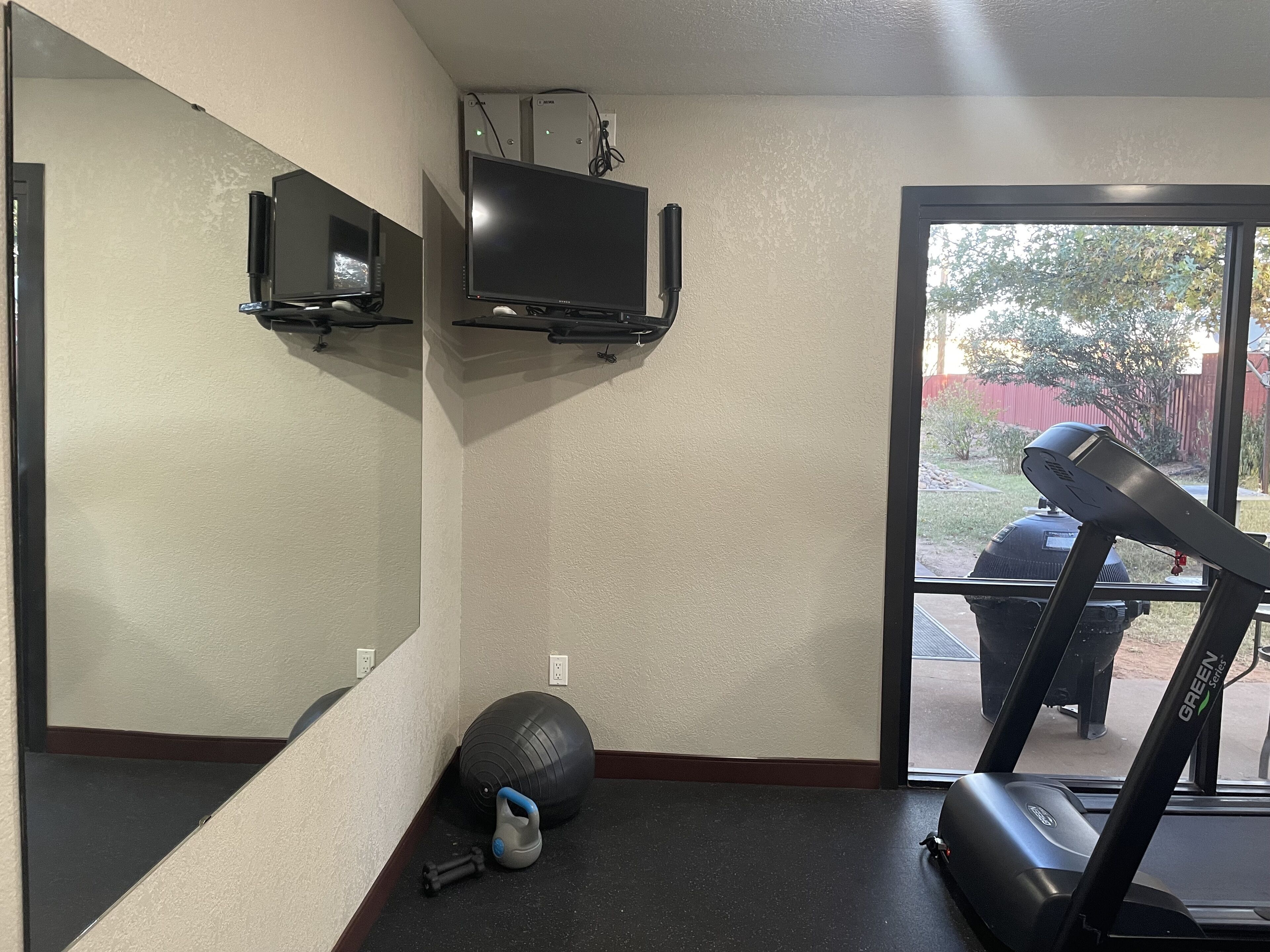 A home gym with a treadmill, exercise ball, and kettlebell.