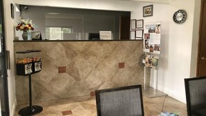 A reception area with a marble counter, a clock, framed pictures, and a bulletin board. - Western Motel Thomasville  (Thomasville)