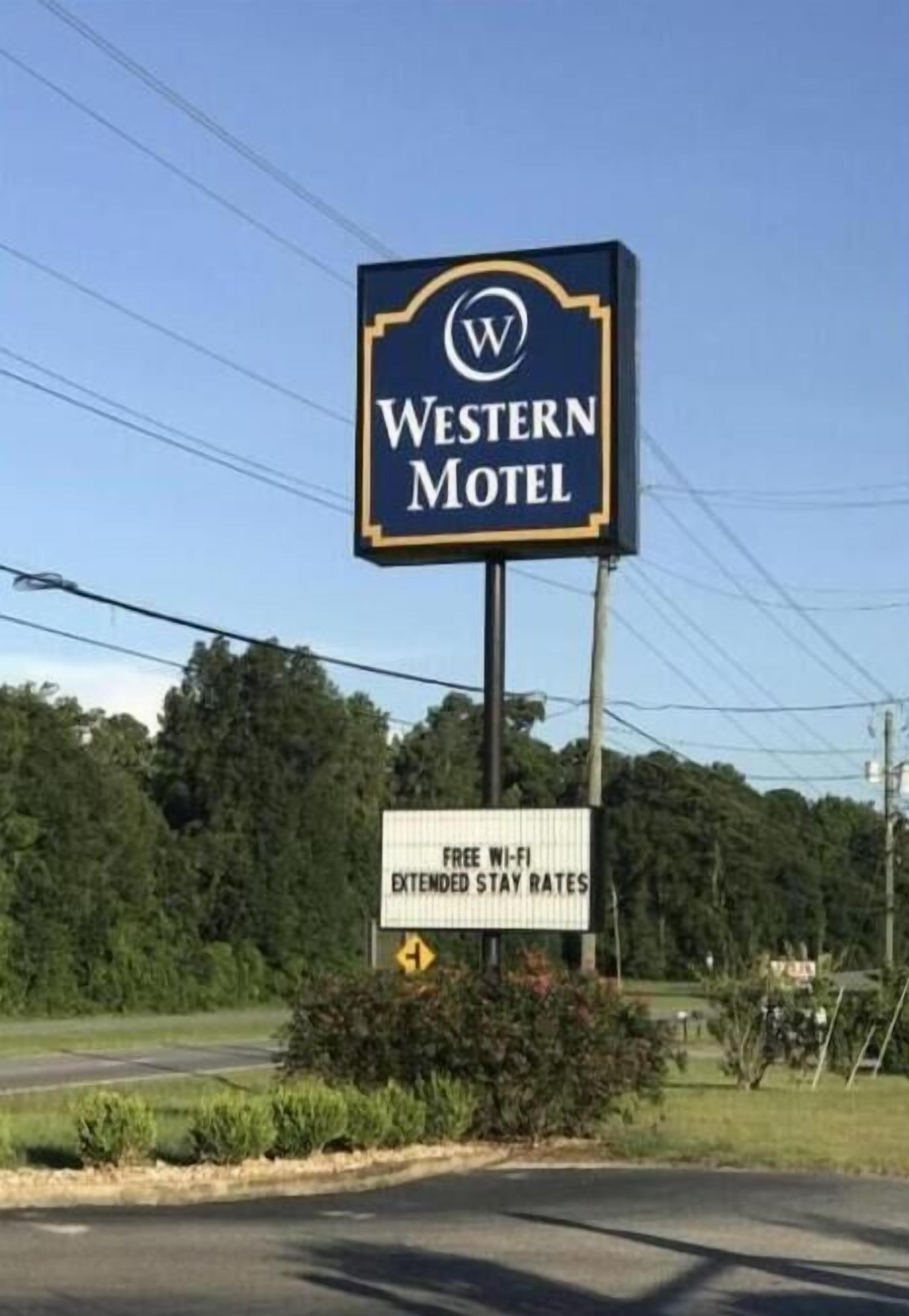 Une enseigne de motel de style occidental indiquant la présence d’une connexion Wi-Fi gratuite et proposant des tarifs pour les séjours de longue durée.