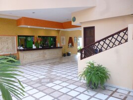 Zona de recepción con suelo de baldosas, un mostrador de recepción y una escalera.